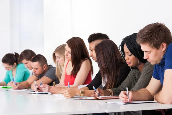 Reihe von College-Studenten schreiben am Schreibtisch — Stockfoto