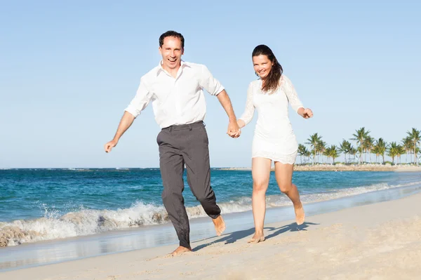 Pareja feliz cogida de la mano mientras corre por la playa —  Fotos de Stock