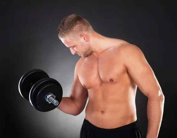 Musculoso hombre levantando pesas en un gimnasio — Foto de Stock