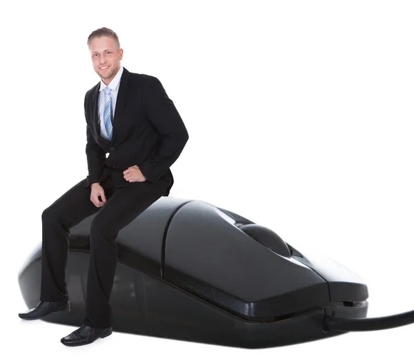 Бизнесмен в костюме сидит на проводной компьютерной мыши — стоковое фото