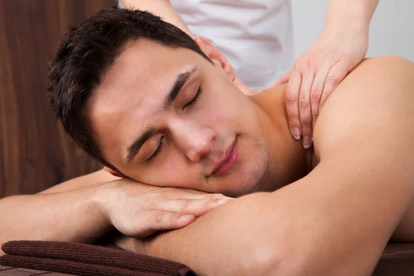 Мужчина, получающий массаж плеч в спа — стоковое фото