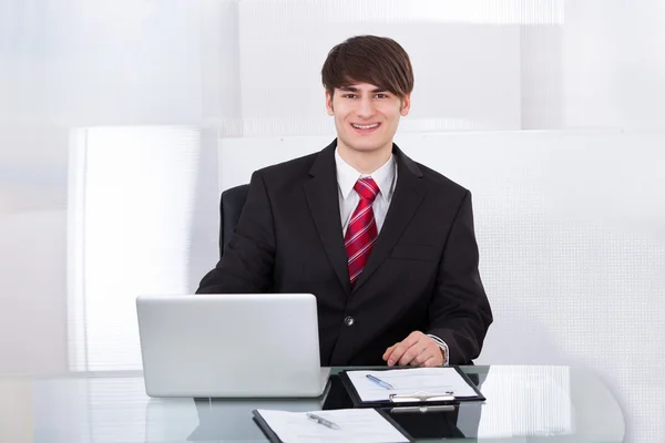 Empresario seguro con el ordenador portátil en el escritorio — Foto de Stock