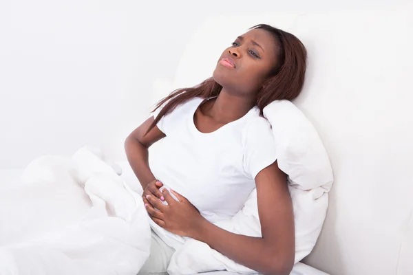 Vrouw lijden buikpijn in bed — Stockfoto