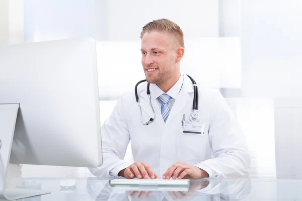 Leende läkare eller konsult som sitter vid ett skrivbord — Stockfoto