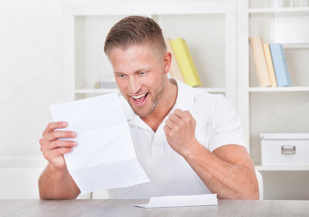 Man cheering in jubilation as he reads a letter