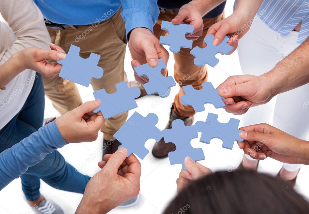 Group of people connecting puzzle pieces