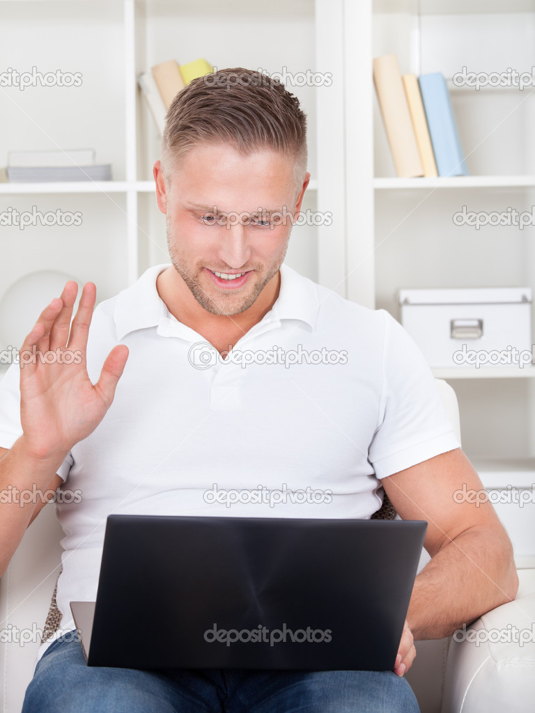 Businessman waving in pleasure to his laptop