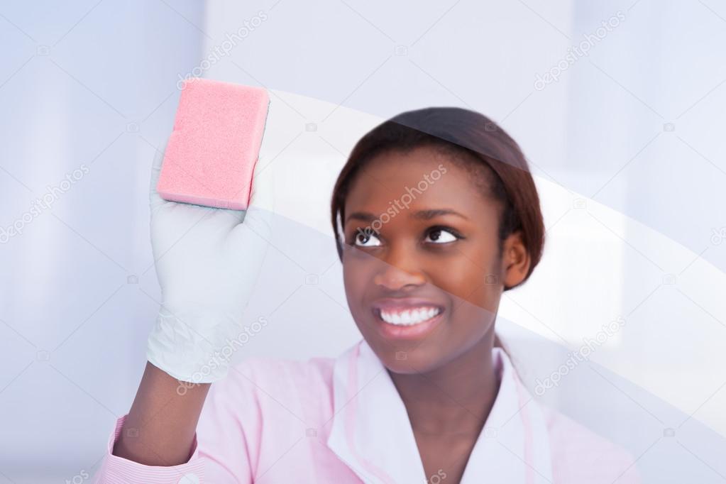Female Housekeeper Cleaning Glass In Hotel