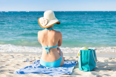 Woman in bikini relaxing on beach towel enjoying the ocean view clipart