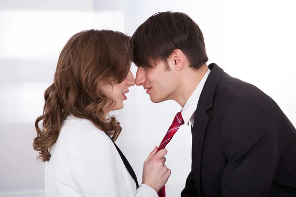 Empresaria tirando del lazo de su colega masculino mientras lo seduce —  Fotos de Stock