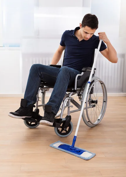 Behinderter wischt Boden, während er im Rollstuhl sitzt — Stockfoto