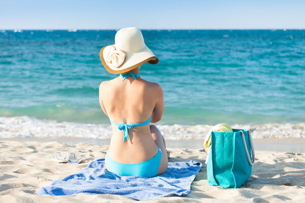 Woman in bikini relaxing on beach towel enjoying the ocean view