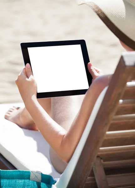 Donna che utilizza tavoletta digitale sulla sedia da spiaggia — Foto Stock