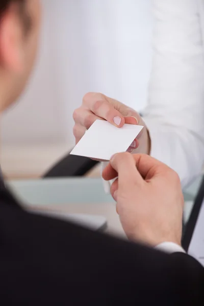 Businessman Giving Visiting Card To Colleague At Desk — Stock Photo, Image