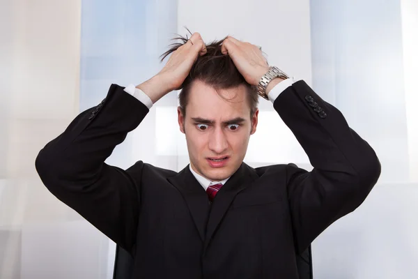 Запутавшийся бизнесмен дергает за волосы — стоковое фото
