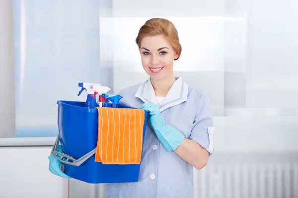 Giovane domestica tenendo forniture per la pulizia — Foto Stock