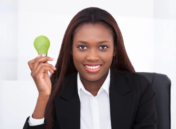 Femme d'affaires tenant l'ampoule électrique verte dans le bureau — Photo