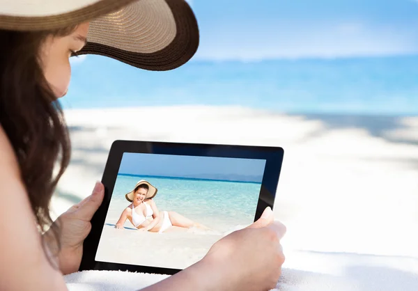 Γυναίκα, κοιτάζοντας την εικόνα της σε ψηφιακή δισκίο στην παραλία — Φωτογραφία Αρχείου
