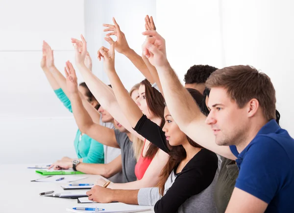 Fila di studenti universitari alzando le mani — Foto Stock