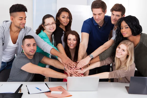 Studenten stapeln Hände am Schreibtisch — Stockfoto