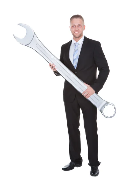 Businessman in a smart suit holding a large metal spanner — Stock Photo, Image