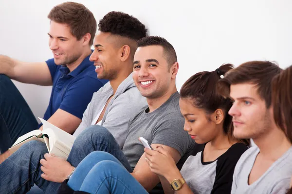 Estudante feliz sentado com colegas — Stockfoto