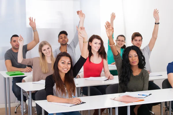 College Students Raising Hands In Classroom — Stock Photo, Image