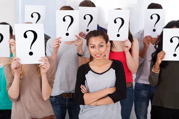 Student Surrounded By Classmates Holding Question Mark Signs — Stock Photo, Image