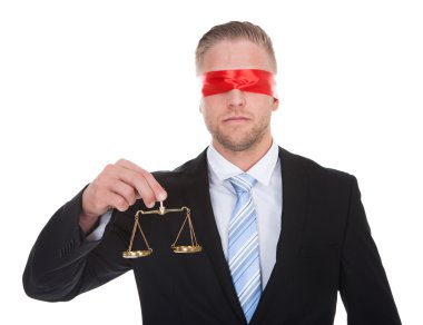 Lawyer with scales of justice wearing a blindfold clipart