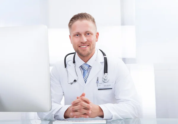 Médico sorridente ou consultor sentado em uma mesa — Fotografia de Stock