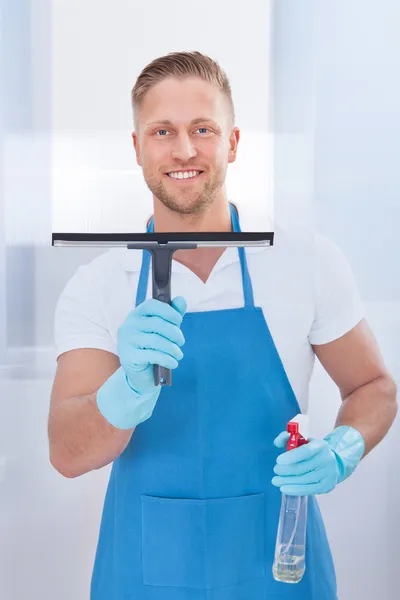 Male janitor using a squeegee to clean a window — Stock Photo, Image