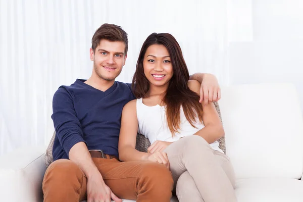 Souriant jeune couple assis sur le canapé — Photo