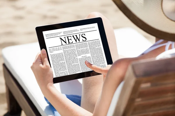 Vrouw leest krant op digitale tablet op strand — Stockfoto