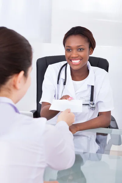 Happy female dentist giving prescription to patient — Stock Photo, Image