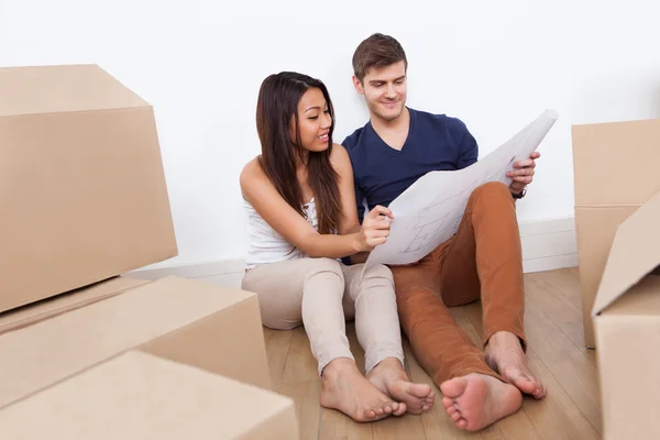 Pareja mirando el plano en un nuevo hogar — Foto de Stock