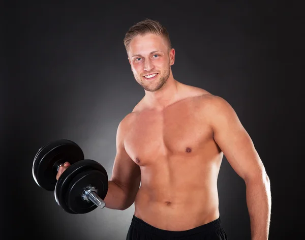 Joven haciendo ejercicio levantando pesas en un gimnasio —  Fotos de Stock