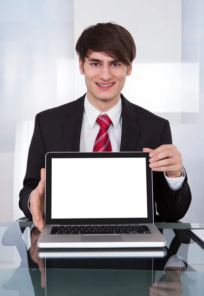 Säker affärsman visar laptop på skrivbordet — Stockfoto