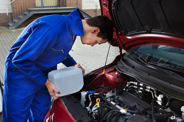 Mechanic gieten antivries in voorruit watertank — Stockfoto