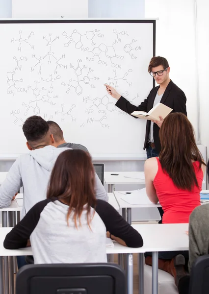 Profesora enseñando fórmulas químicas a estudiantes universitarios — Foto de Stock