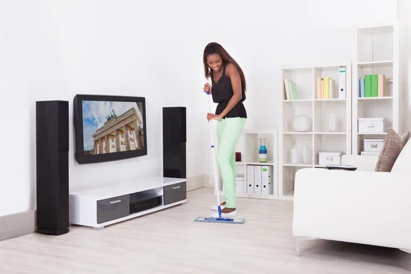 Mulher afro-americana limpeza chão na sala de estar — Fotografia de Stock