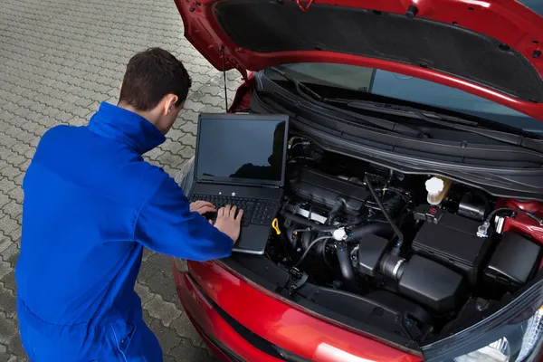 Mechanik užívající laptop při opravě vozu — Stock fotografie
