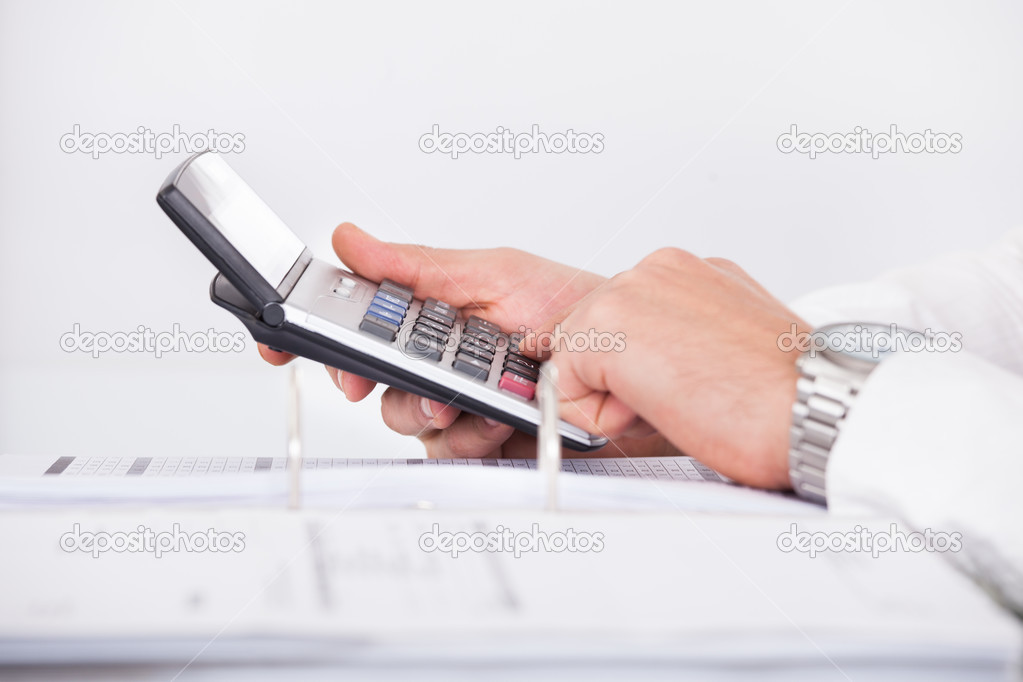 Businessman Using Calculator In Office