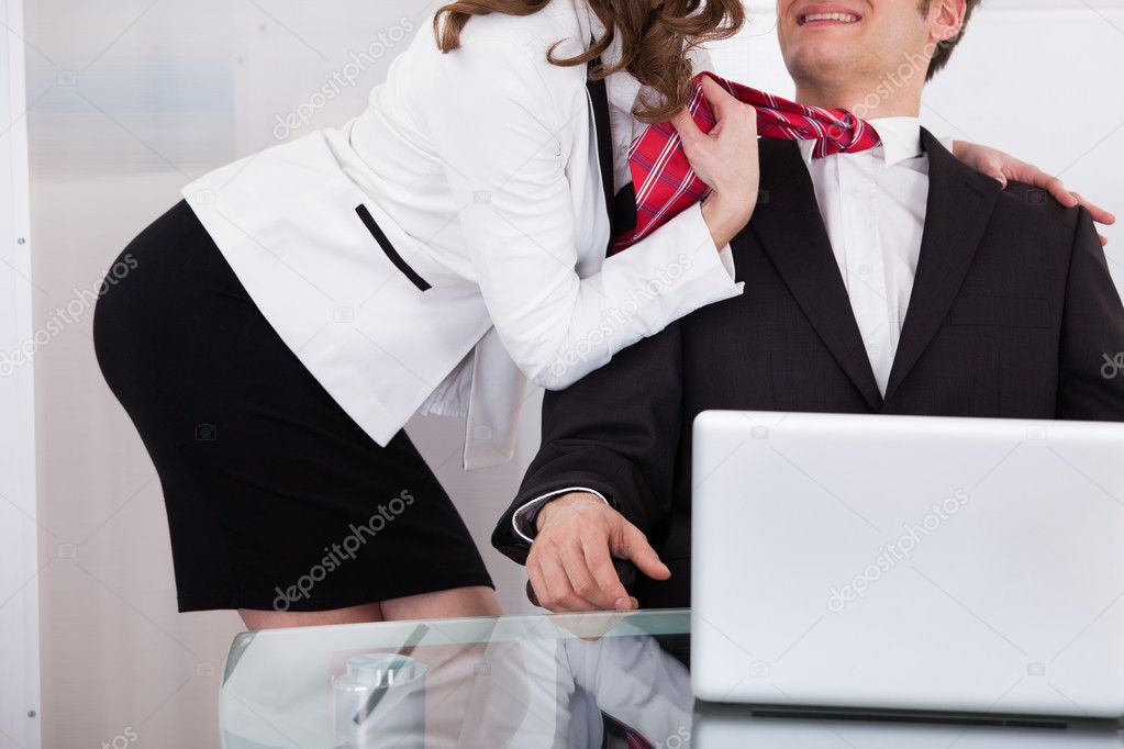 Businesswoman Pulling Male Colleague's Tie While Seducing Him