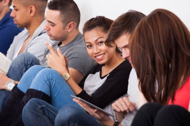 Üniversite öğrencisi sınıf arkadaşlarıyla otururken gülümseyen