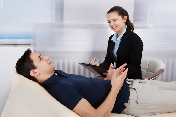 Psicólogo escribiendo notas mientras paciente acostado en la cama — Foto de Stock