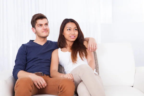 Souriant jeune couple assis sur le canapé — Photo