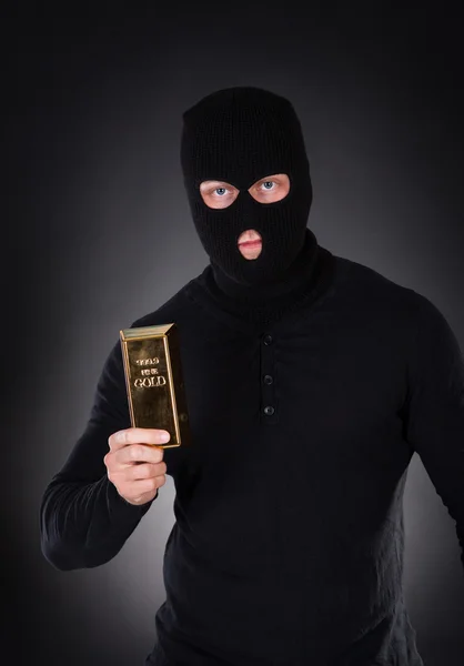 Robber holding a gold bullion bar — Stock Photo, Image