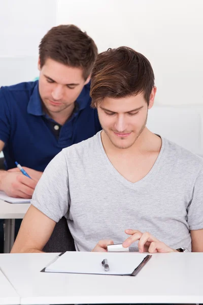 Jonge mannelijke universiteitsstudent met behulp van mobiele telefoon — Stockfoto