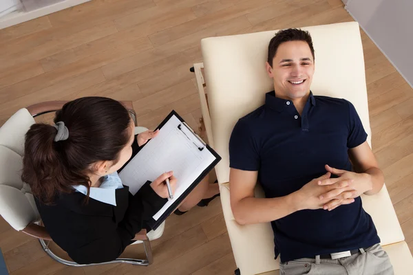 Paciente masculino comunicándose mientras el psicólogo escribe notas — Foto de Stock