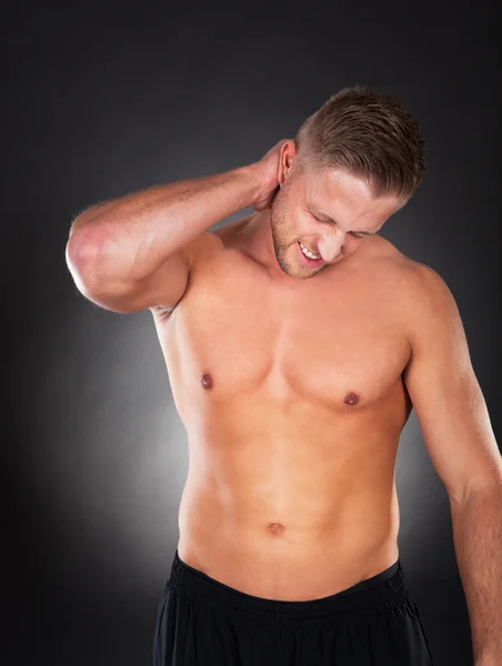 Fit muscular man massaging his neck in pain — Stock Photo, Image